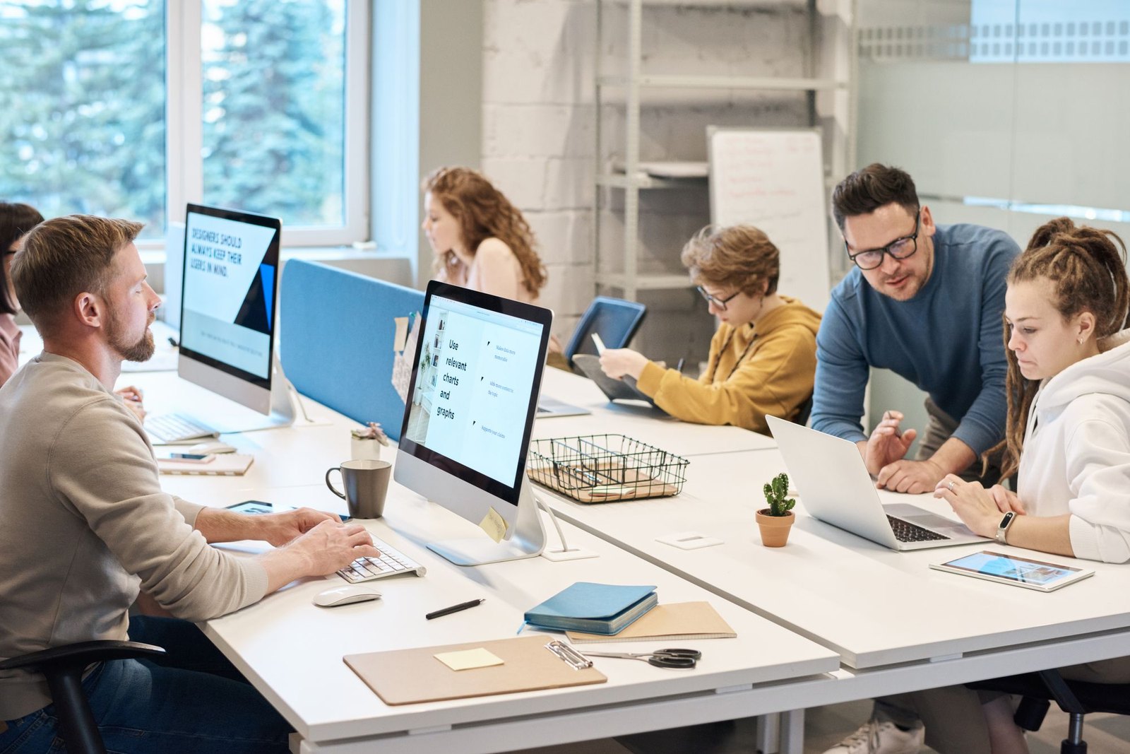 A team working together around desktop computers in a bright office