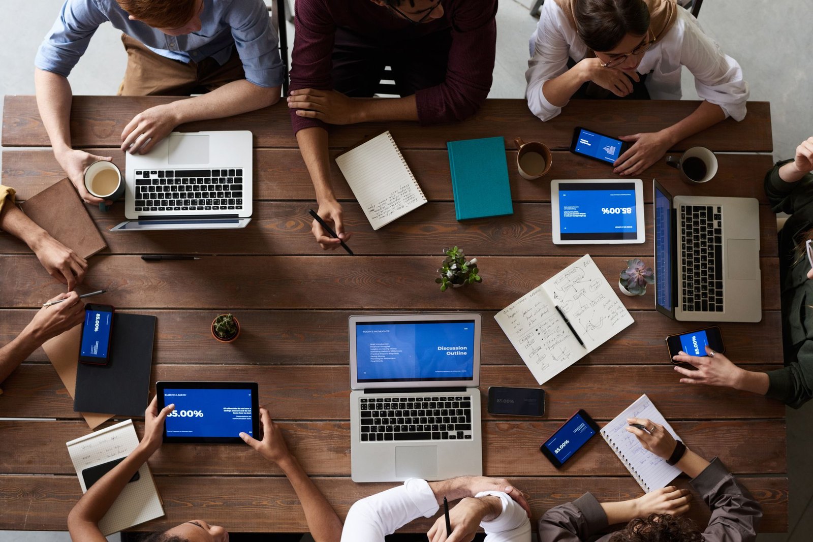 An overhead view of a team coordinating work across laptops and notes
